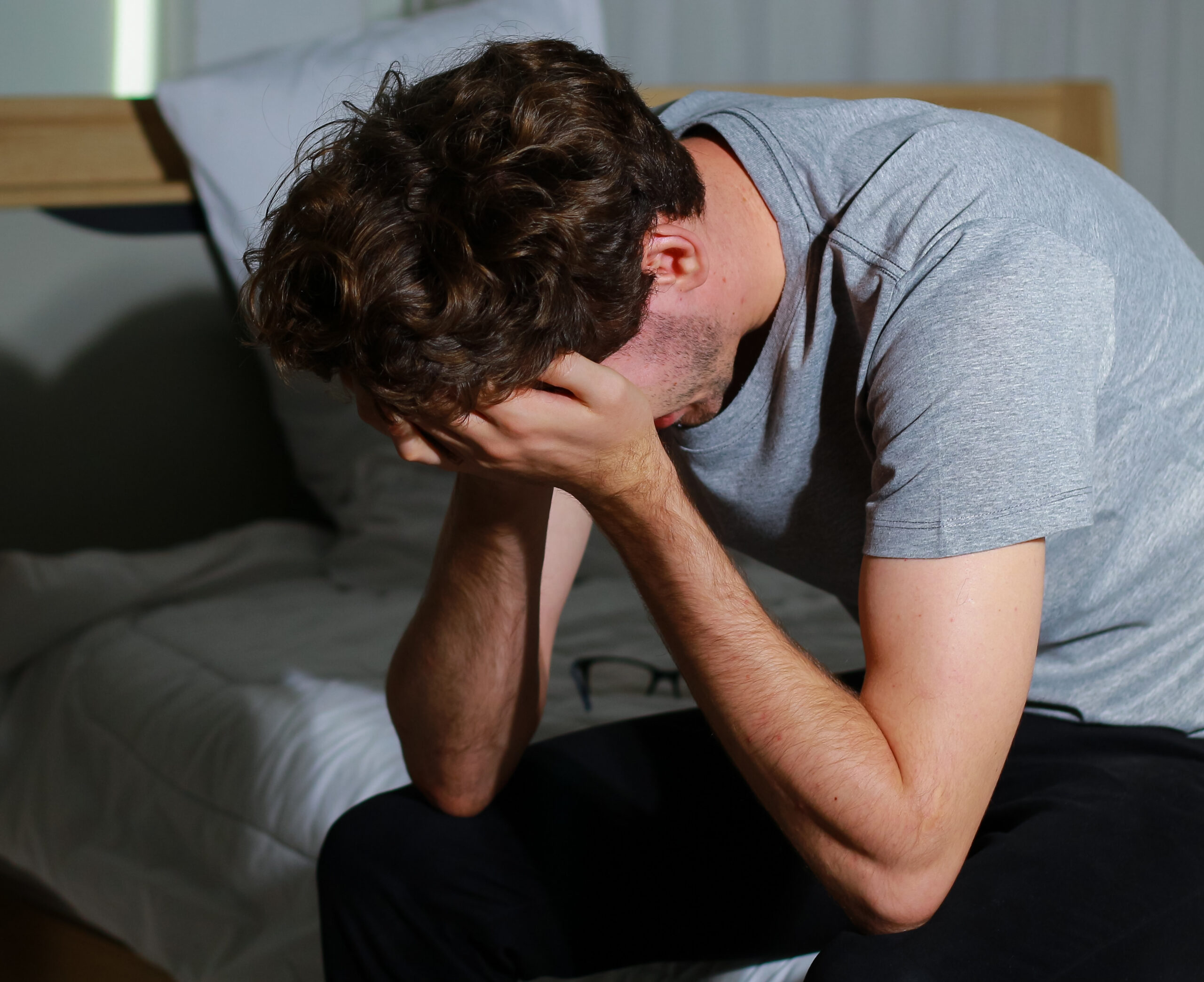 Man sits in the bedroom stressed out due to unemployment. The co